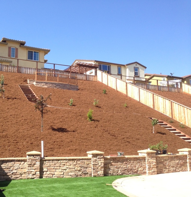Stacked-stone retaining wall terracing a hillside with new plantings
