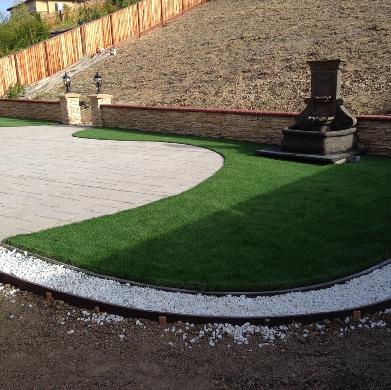 Paver drive curving around lawn with stone fountain feature