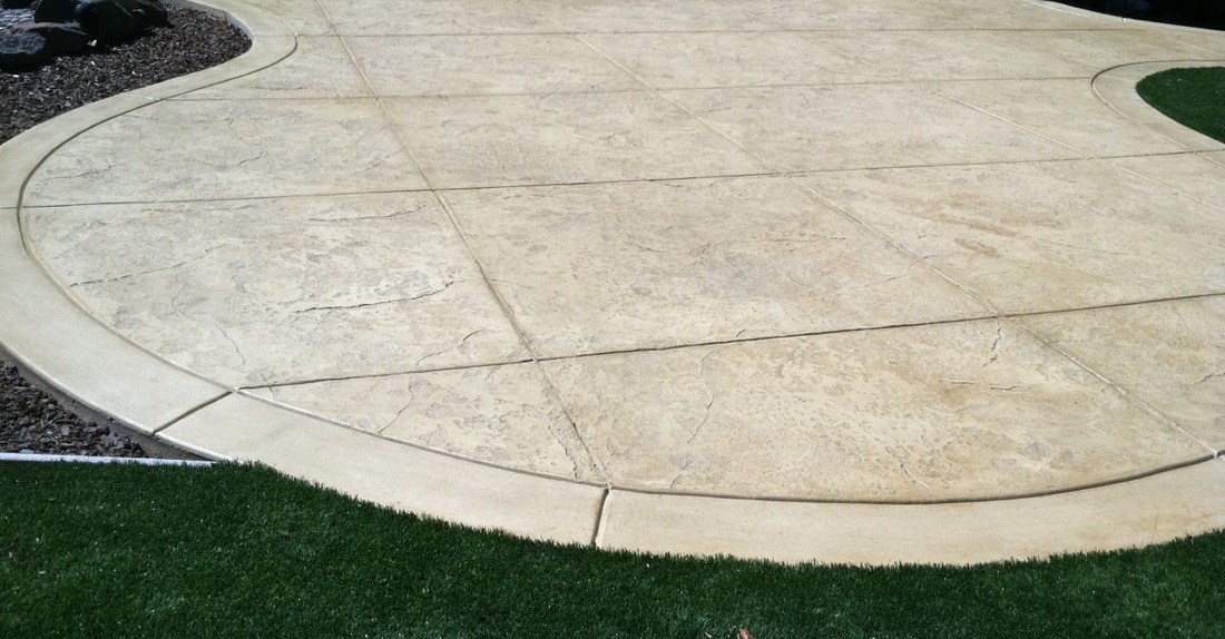 Stamped concrete patio with curved scored joints bordering a lawn